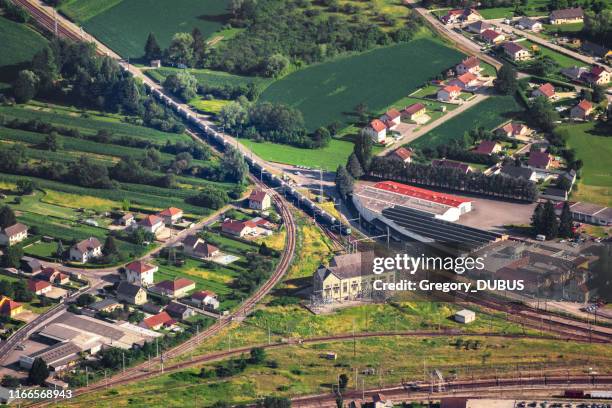 vue aérienne sur le train de marchandises arrivant sur la jonction de la voie ferrée de la ville de culoz, avec la structure du bâtiment ancien, au milieu de français campagne en été, département de l'ain, région auvernge-rhône-alpes - train de marchandises photos et images de collection