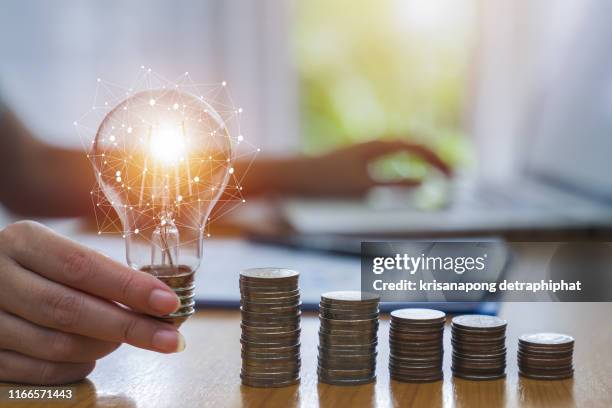 business accounting with saving money with hand holding lightbulb concept financial background - saving electricity stock pictures, royalty-free photos & images