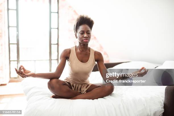 afrikanische frau macht yoga zu hause - yoga kissen stock-fotos und bilder