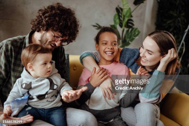 gelukkige familie zittend op de bank - adoption stockfoto's en -beelden