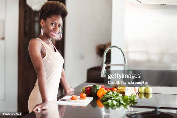african woman preparing a vegan meal at home - reading cookbook stock pictures, royalty-free photos & images