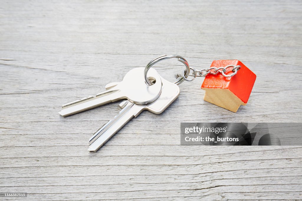 High angle view of keyring with a small red house and keys on wooden background