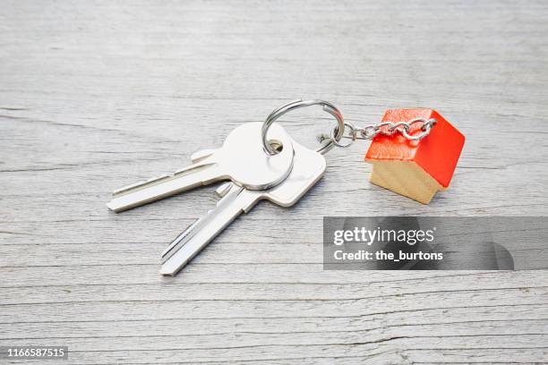 high angle view of keyring with a small red house and keys on wooden background - schmuckanhänger stock-fotos und bilder