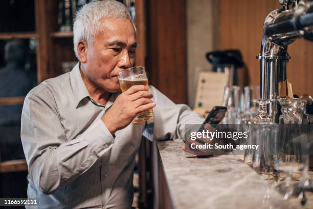 senior gentleman drinking beer in pub alone - senior men beer stock pictures, royalty-free photos & images