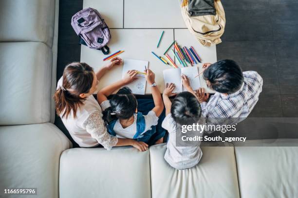 parents doing homework with daughter and son at home - homework table stock pictures, royalty-free photos & images