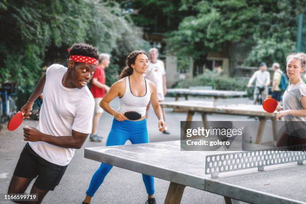 jóvenes jugando al tenis de mesa alrededor - table tennis fotografías e imágenes de stock