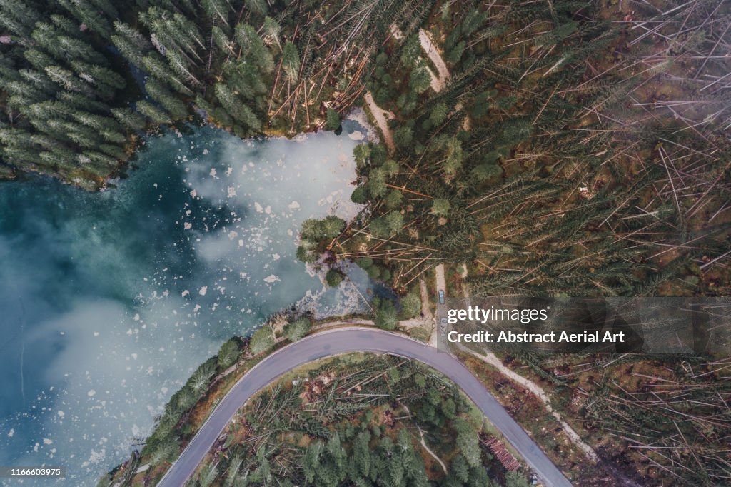 Aerial shot at the edge of Lake Carezza showing storm damaged forest, Dolomites, Italy