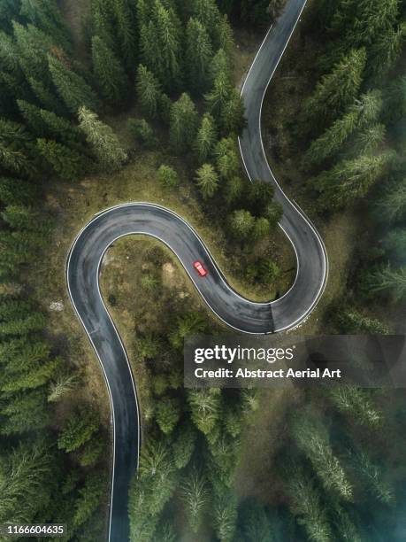 a car driving on a winding forest road seen from directly above, dolomites, italy - ワインディングロード　車 ストックフォトと画像