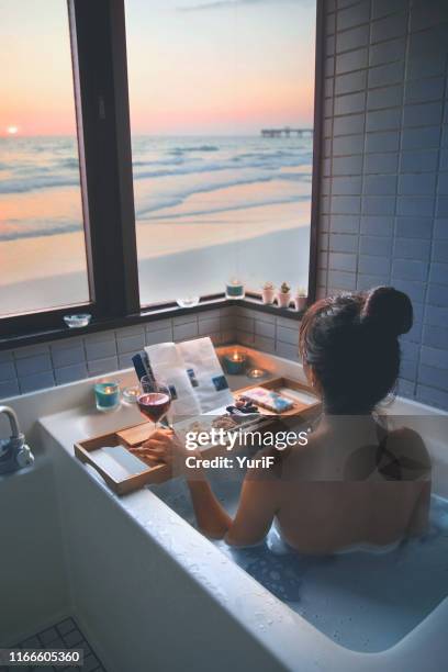 woman looking at the sunset from the bathroom - japanese women bath stock pictures, royalty-free photos & images