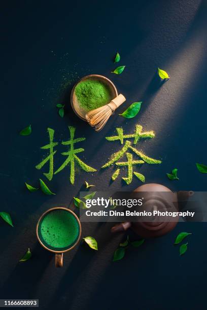 kanji meaning matcha on a dark background with teapot, bamboo whisk, matcha tea and leaves. food typography flat lay with japanese aestetic. - powder tea stock pictures, royalty-free photos & images