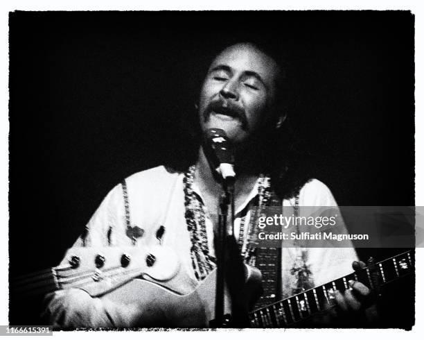 David Crosby of rock band “The Byrds” smiling as he performs in a club in a frontal, waist-high view, eyes half closed, with a mic, circa 1967 in Los...