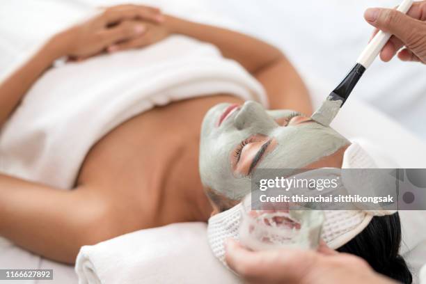 close up of applying facial mask on woman's face in a beauty spa - máscara facial fotografías e imágenes de stock