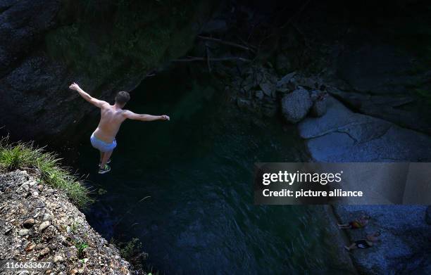 August 2019, Bavaria, Oberstaufen: A young man in the Buchenegger waterfalls jumps from a rock into a pump ten metres below. Photo: Karl-Josef...
