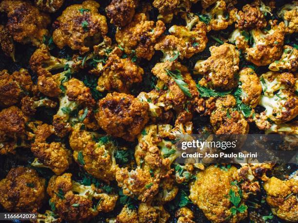 vegan dish, baked cauliflower on a dark tray - comida vegetariana stockfoto's en -beelden