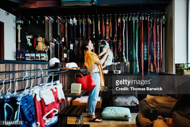 Smiling woman holding up dog while shopping in pet store