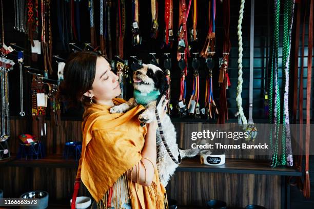 woman holding pet dog while shopping in pet store - shopping candid stock-fotos und bilder