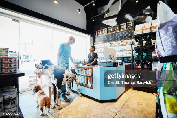 smiling pet store owner helping customer with dogs check out - pet equipment stock-fotos und bilder