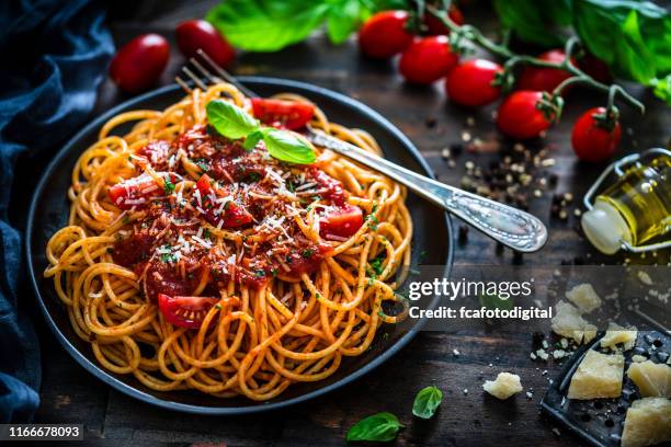 espaguetis con salsa de tomate rodado según una mesa de madera rústica - espaguete fotografías e imágenes de stock