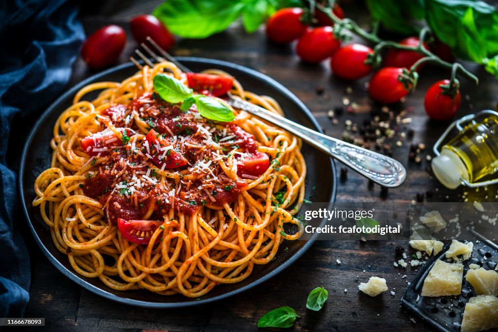 Spaghetti with tomato sauce shot on rustic wooden table