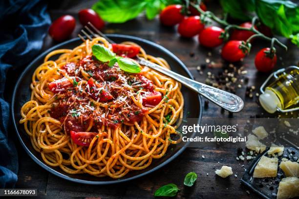 spaghetti with tomato sauce shot on rustic wooden table - sauce stock pictures, royalty-free photos & images