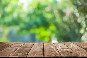 Backgrounds: Empty wooden table with defocused green lush foliage at background