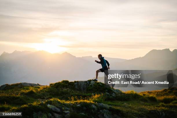 trail runner traverses mountain ridge crest - sport determination stock-fotos und bilder