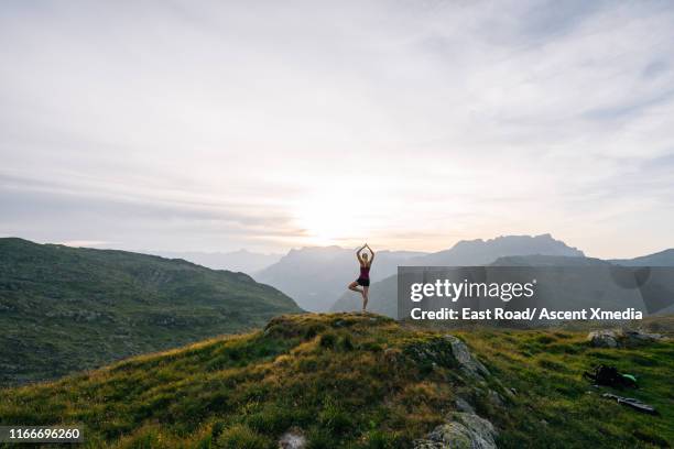 woman performs yoga moves on mountain summit - sunrise yoga foto e immagini stock