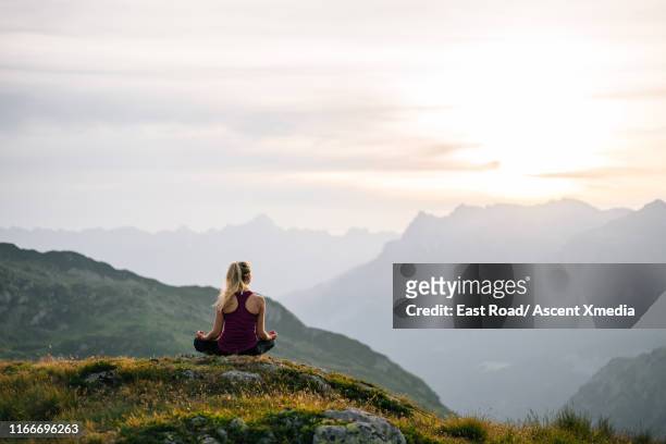 woman performs yoga moves on mountain summit - meditation natur stock-fotos und bilder