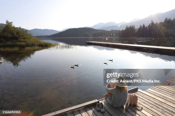 woman relaxes on wooden pier above lake, contemplative - floating on water stock pictures, royalty-free photos & images