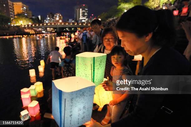 Man prepares to float a candle lit paper lantern on the river during an event to commemorate the 74th anniversary of the atomic bombing of Hiroshima...