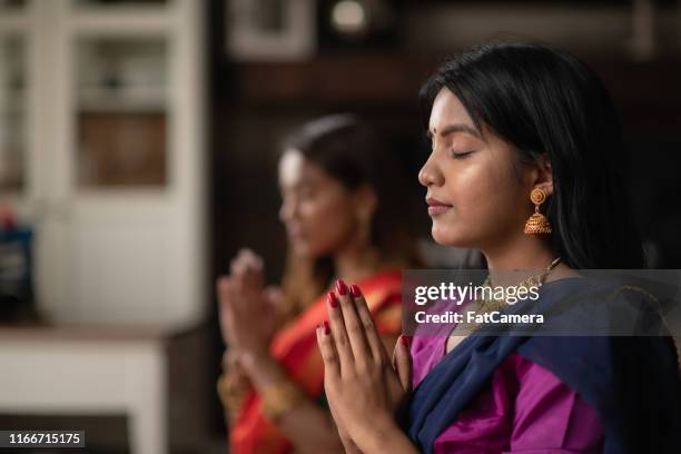 indiase vrouwtjes bidden een middag in hun woonkamer - hinduism stockfoto's en -beelden