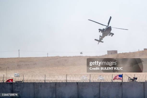 This picture taken on September 8, 2019 shows an US army helicopter flying over Turkish and US armoured vehicles which take part in their first joint...