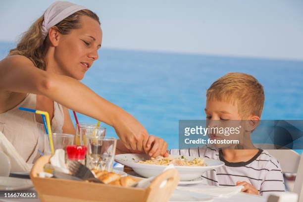 mor och son med trevlig tid på restaurang - cafe at beach bildbanksfoton och bilder