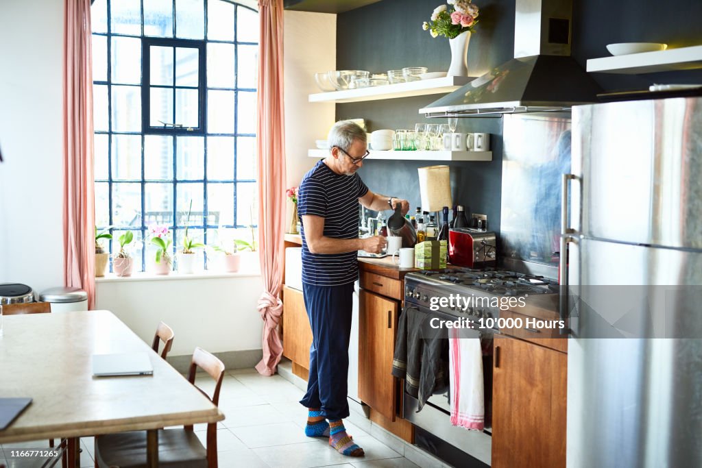 Mature man making cup of tea at home in kitchen