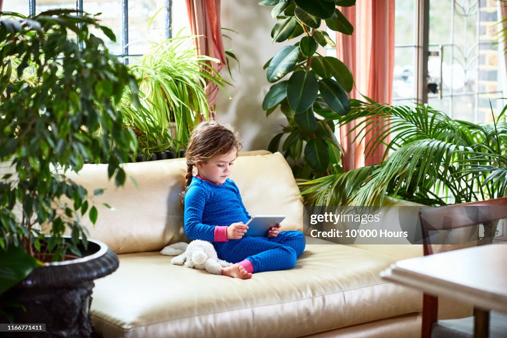 Young girl on sofa using digital tablet