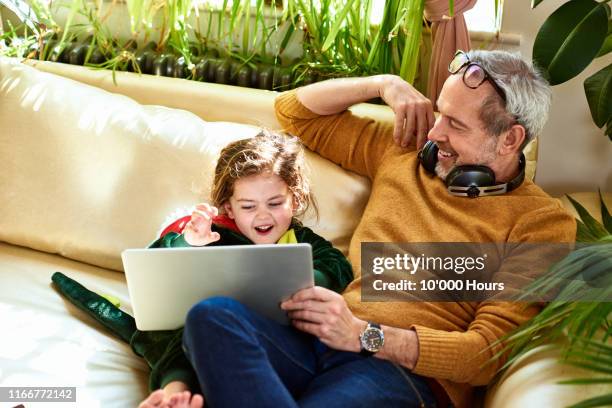 mature father watching online tv with daughter in dinosaur costume - 叔父 ストックフォトと画像