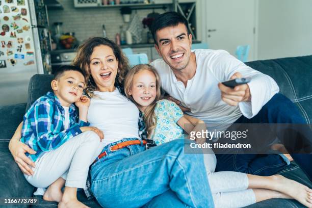 familia viendo la televisión - remote controlled fotografías e imágenes de stock