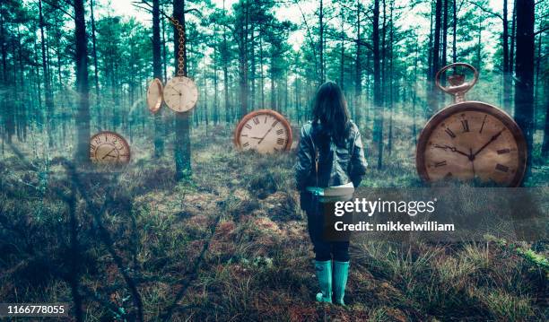 concepto del tiempo con la mujer en el bosque rodeada de grandes relojes - perder el tiempo fotografías e imágenes de stock