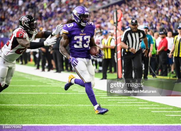 Dalvin Cook of the Minnesota Vikings runs with the ball for a touchdown as Keanu Neal of the Atlanta Falcons runs defense in the first quarter of the...