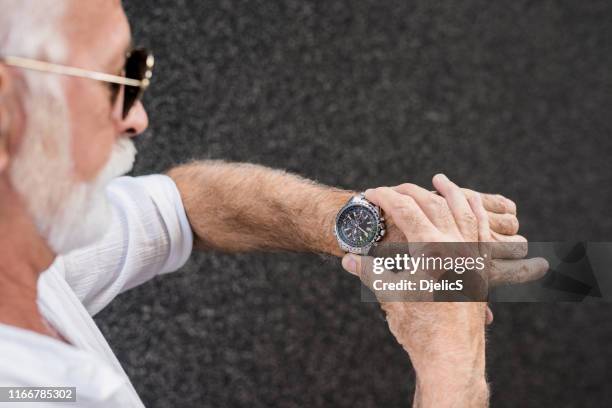 senior man checking time on a luxury watch. - luxury watches stock pictures, royalty-free photos & images