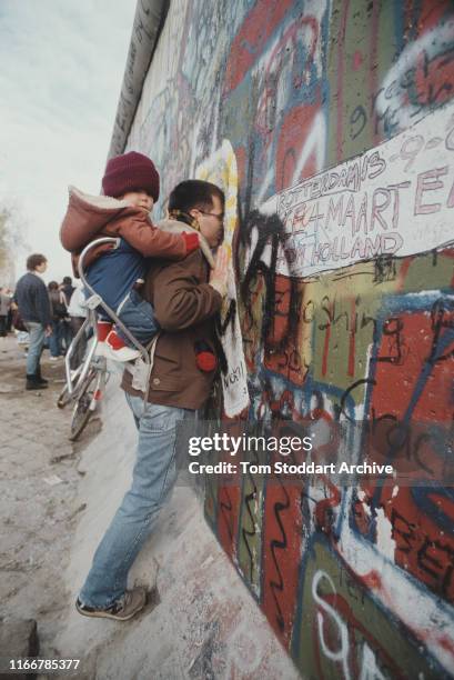 West Berliners peer through gaps in the Berlin Wall, 10th-11th November 1989. The border was opened on 9th November and demolition of the wall by...