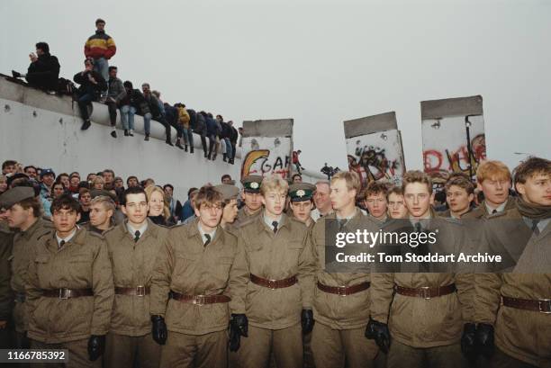 East German border guards stand in line in the former 'death strip' on the Eastern side of the Berlin Wall, where it divided Potsdamer Platz, after...