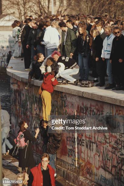 People climb onto the Berlin Wall to celebrate after the border between East and West Berlin was opened, 10th-11th November 1989. The border was...