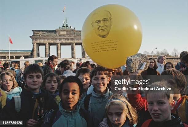 Group of children near the Brandenburg Gate show off their souvenir pieces of the Berlin Wall on the morning of 10th November 1989. One of them holds...