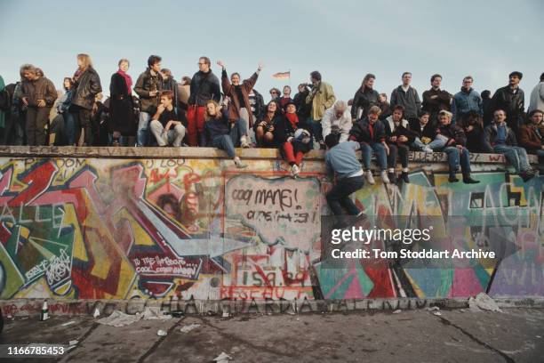 Crowds celebrate on top of the Berlin Wall after the border between East and West Berlin was opened, November 1989. The border was opened on the...