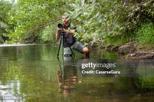Young Photographer capturing an image from an uncomfortable position in the middle of the river
