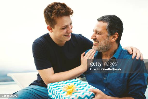 hijo dando un regalo para su padre en el día del padre. - fathers day fotografías e imágenes de stock