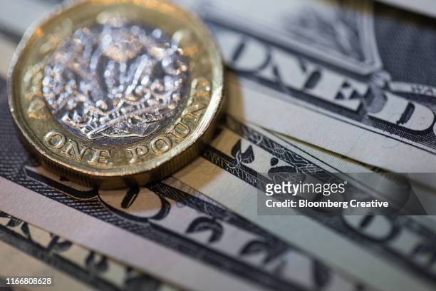 british one pound coin and american one dollar bills - engelse valuta stockfoto's en -beelden