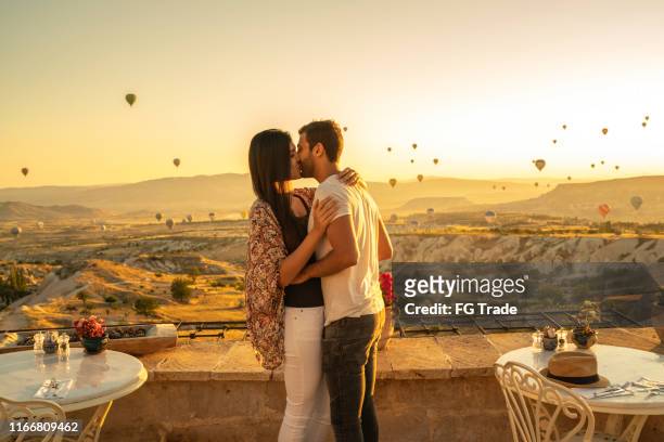 junges paar küssen in sonnenuntergang während ballonfestival - cappadocia hot air balloon stock-fotos und bilder