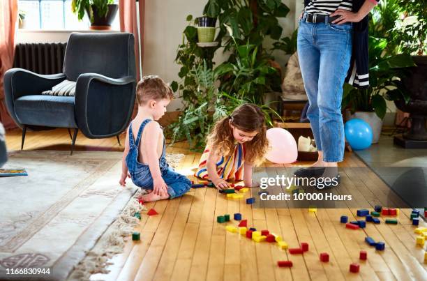 two children playing with wooden blocks on wooden floor - strict parent stockfoto's en -beelden